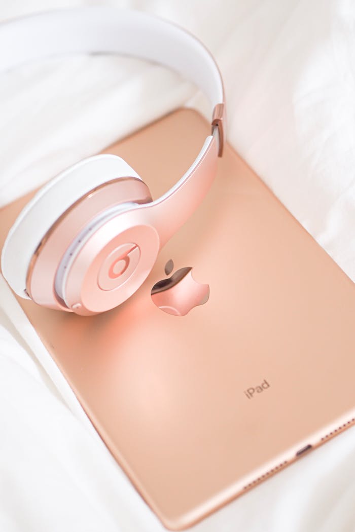 Stylish rose gold headphones resting on an iPad, a modern tech accessory display.
