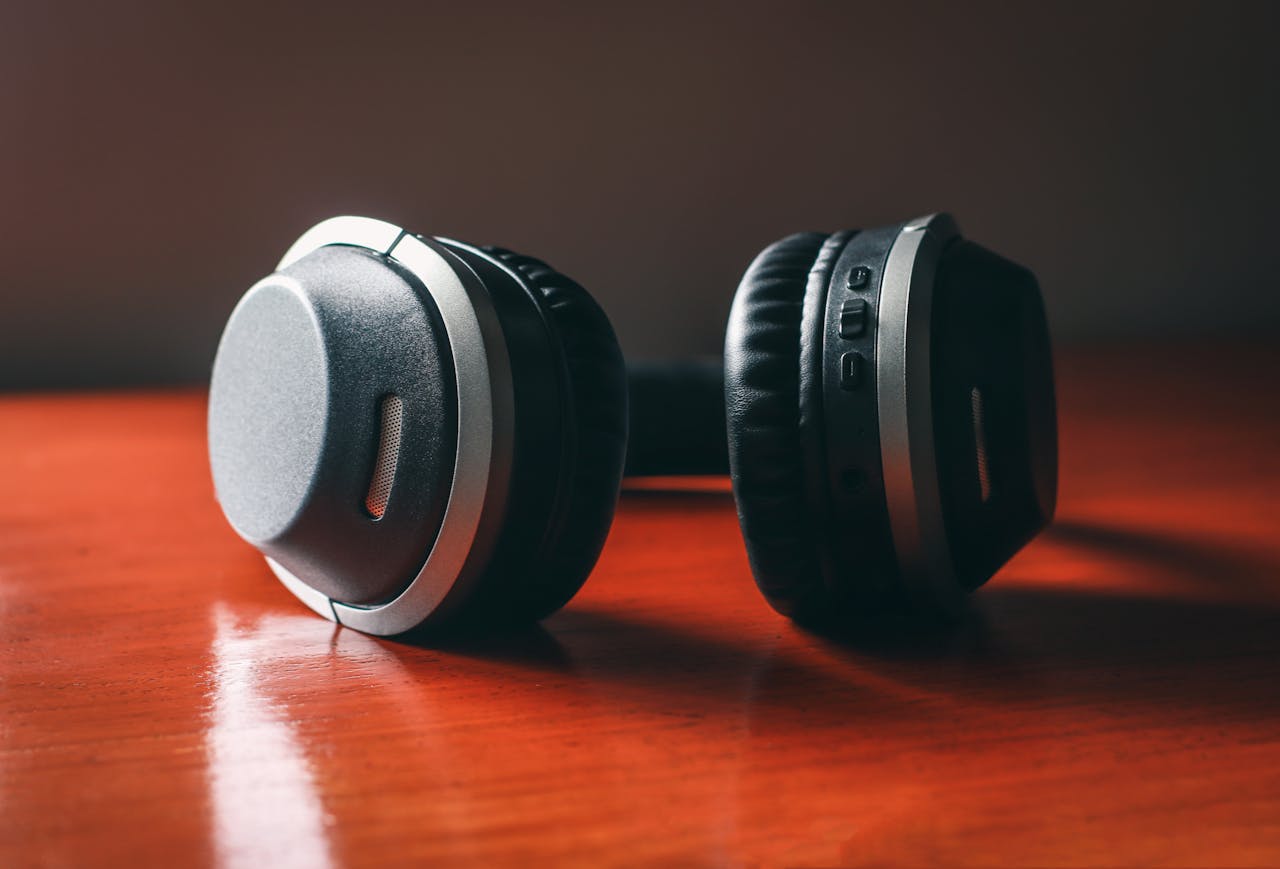 Close-up of wireless headphones on a wooden table, emphasizing design and technology.